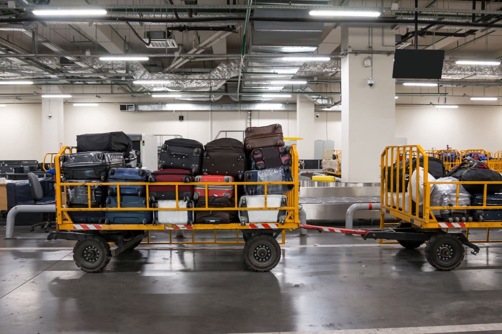 Dutzende Koffer liegen auf Transportwagen im Flughafen 