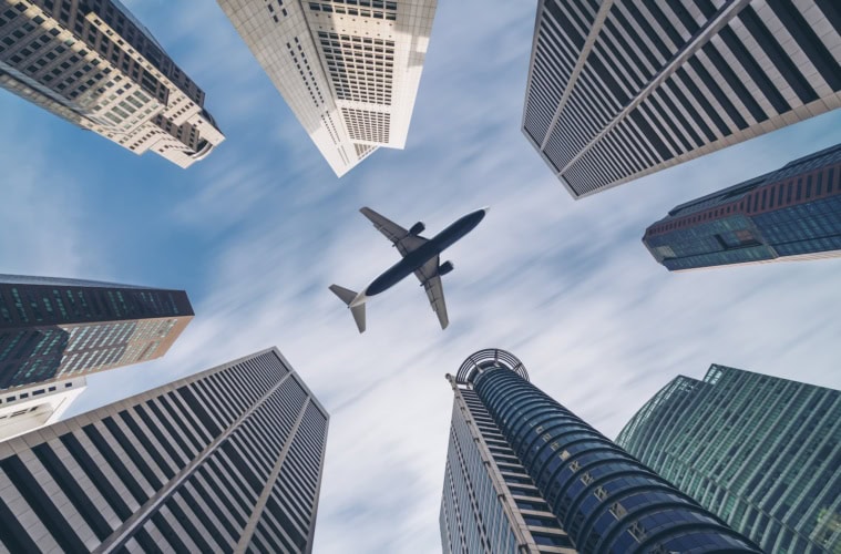 Ein Flugzeug fliegt über den Hochhäusern von Singapur.