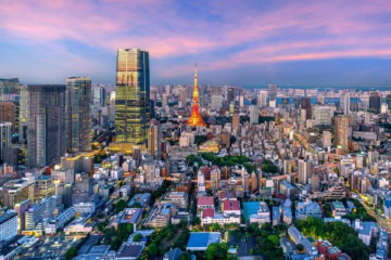 Blick von einer Aussichtsplattform auf Tokio in der Abenddämmerung, im Zentrum prominent der rot-weiße Fernsehturm