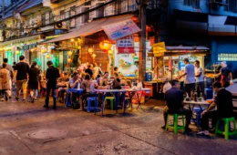 Menschen sitzen vor einem Restaurant in Bangkok.