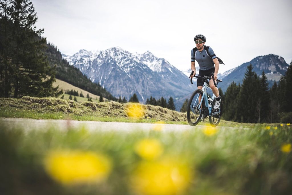 Junger Fahrradfahrer radelt zwischen Butterblumen-Wiesen