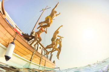 Familie springt von Segelboot ins Wasser