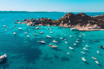 Boote in der türkisen Bucht in Sardinien
