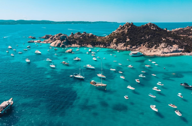 Boote in der türkisen Bucht in Sardinien