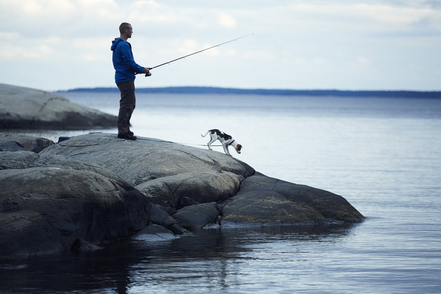 Mann angelt in Schweden mit Hund