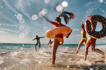 Zwei Männer und drei Frauen springen freudig ins Meer
