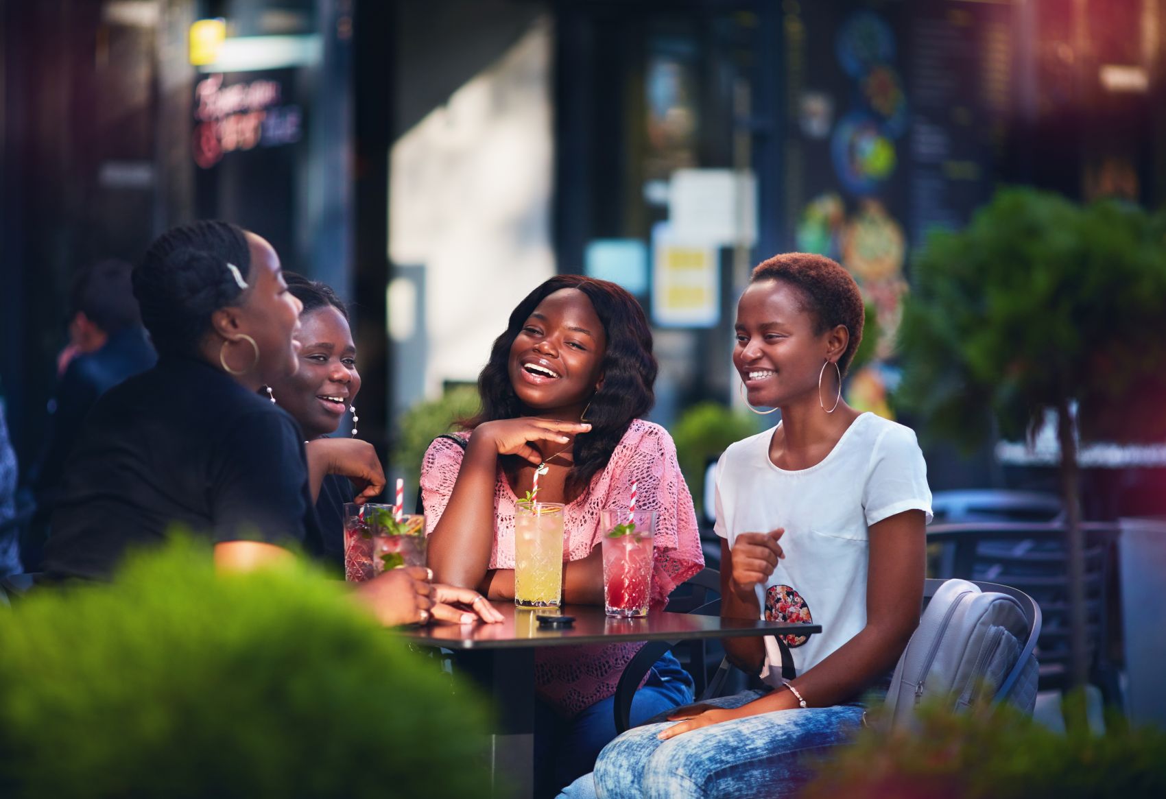 Vier Afroamerikanerinnen sitzen im Restaurant am Tisch und unterhalten sich lachend