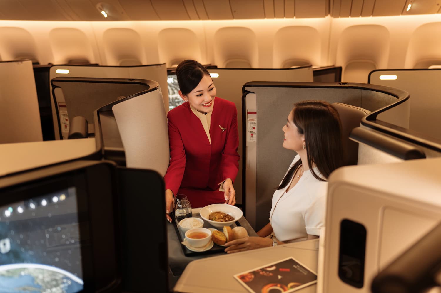 Frau serviert einer Passagierin in der Business bei Cathay Pacific Essen