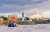 Ein Paar sitzt vor einem Strandkorb mit einer Flasche Bier beim Sonnenuntergang am Timmendorf Strand von Poel