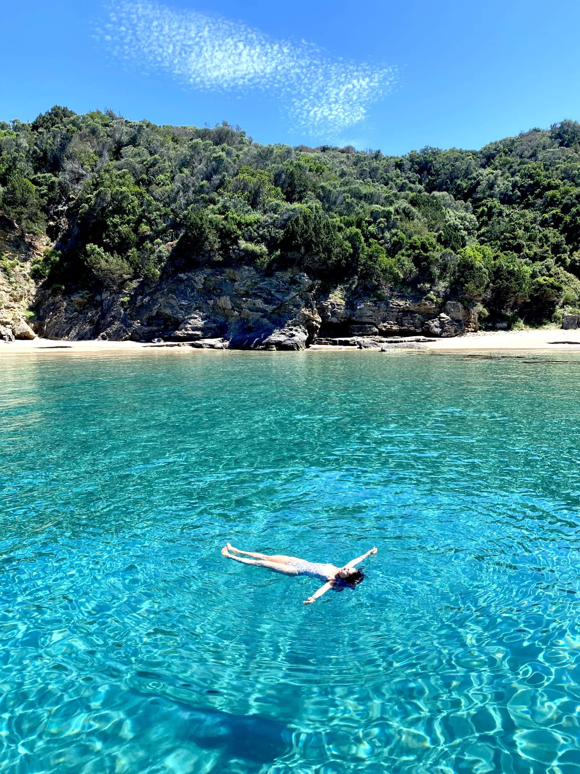 Frau schwimmt im kristallklaren Wasser in einer Bucht im Süden von Zakynthos