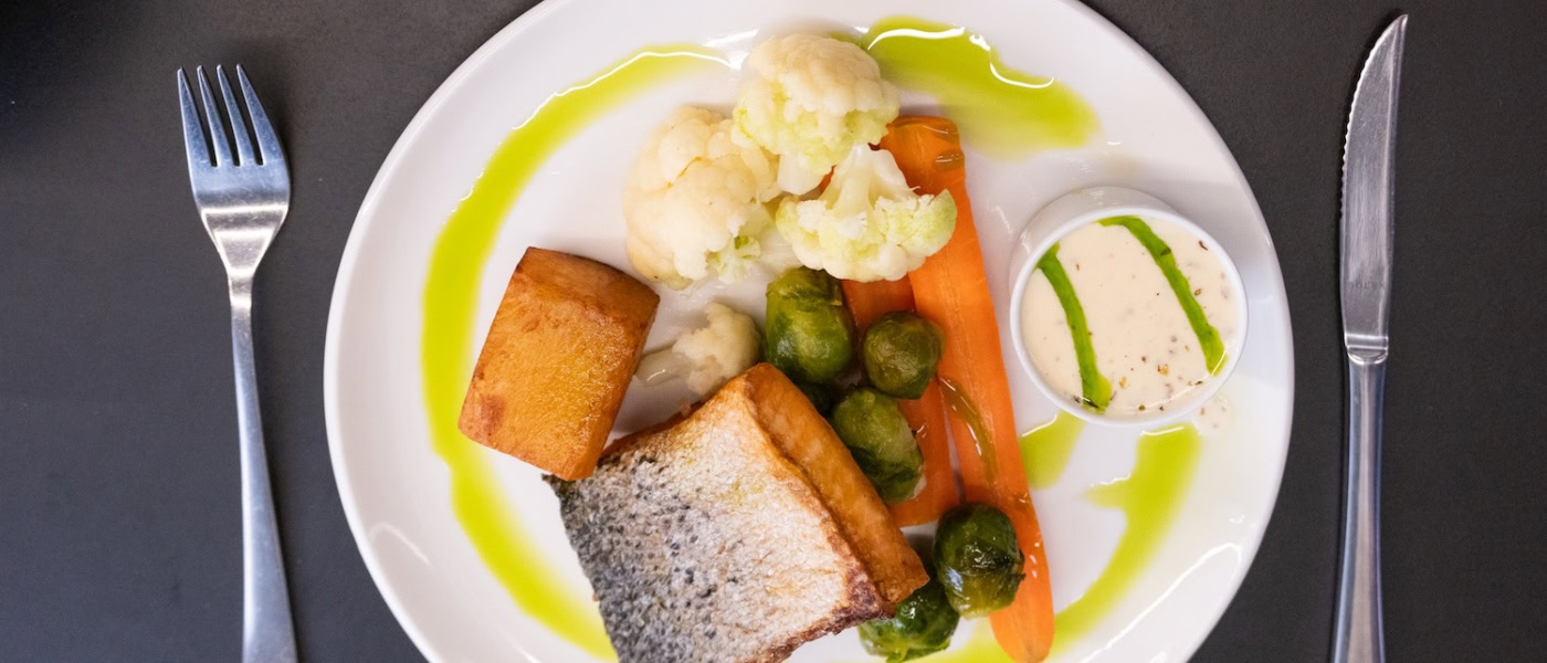 Wildlachs angerichtet mit Blumenkohl und Kartoffeln auf einem Teller