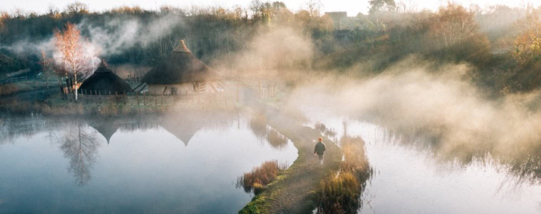 Mann läuft über einen Steg im Nebel im The Irish Heritage Park in Irland