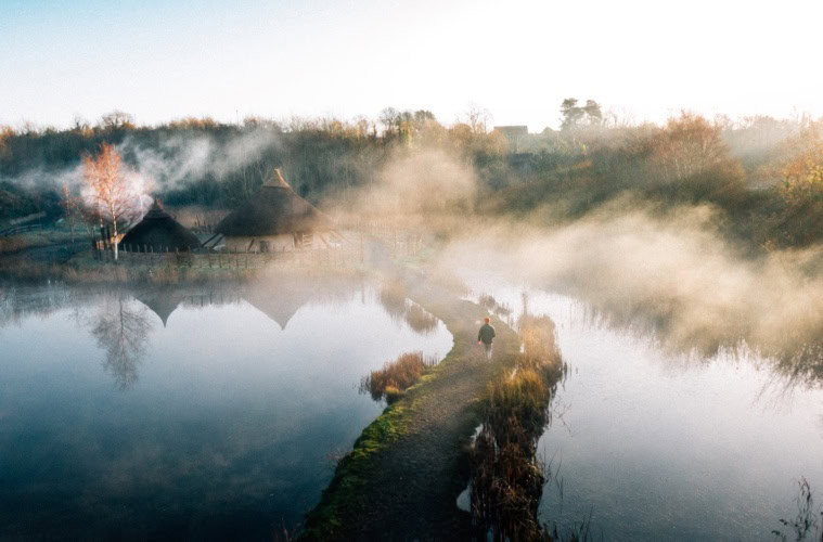 Mann läuft über einen Steg im Nebel im The Irish Heritage Park in Irland