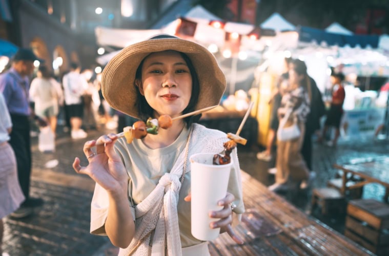 Frau isst Gegrilltes vom Spieß