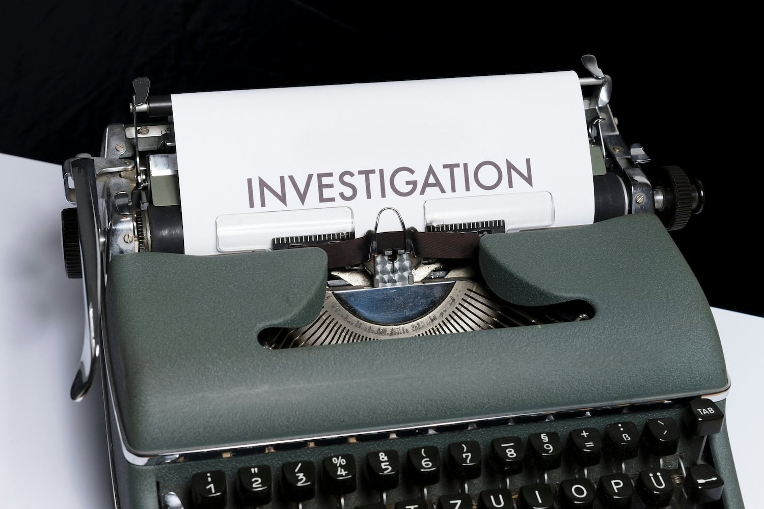 Schreibmaschine mit einem Zettel, auf dem "Investigation" steht