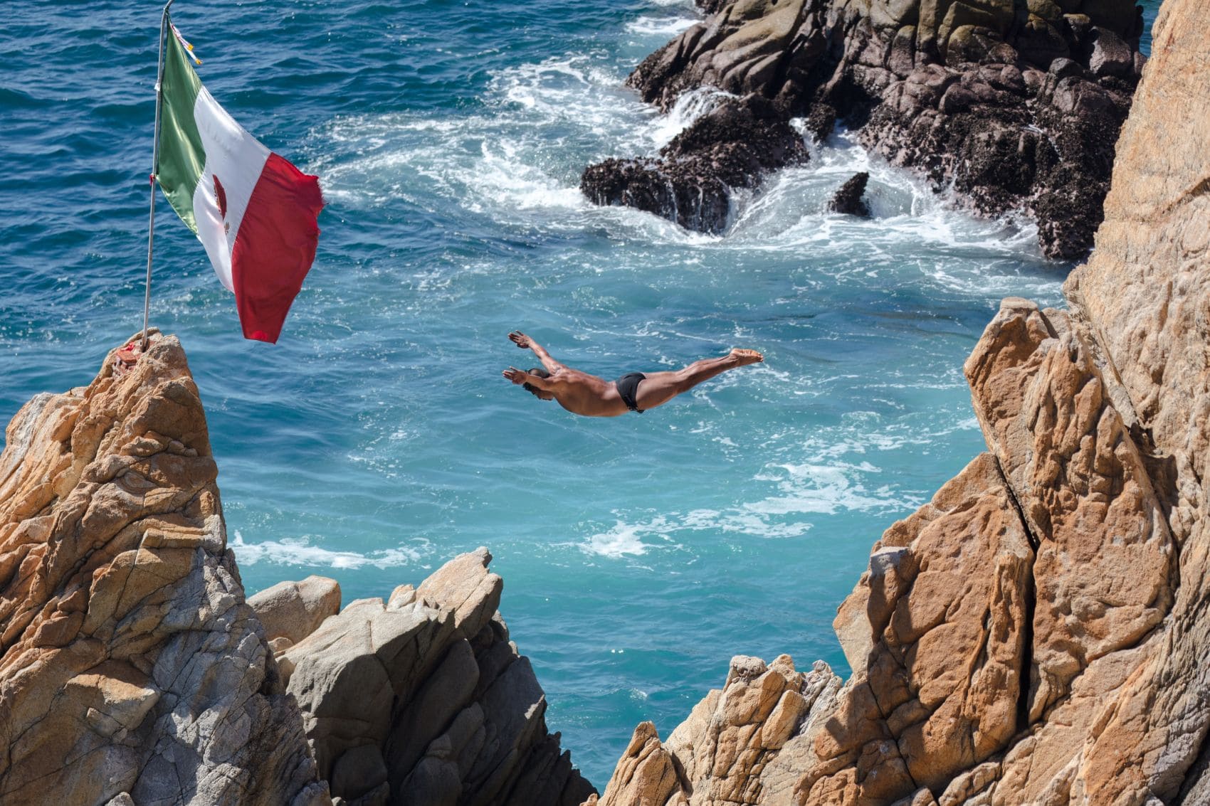 Mann springt in La Quebrada von den Klippen ins Meer 