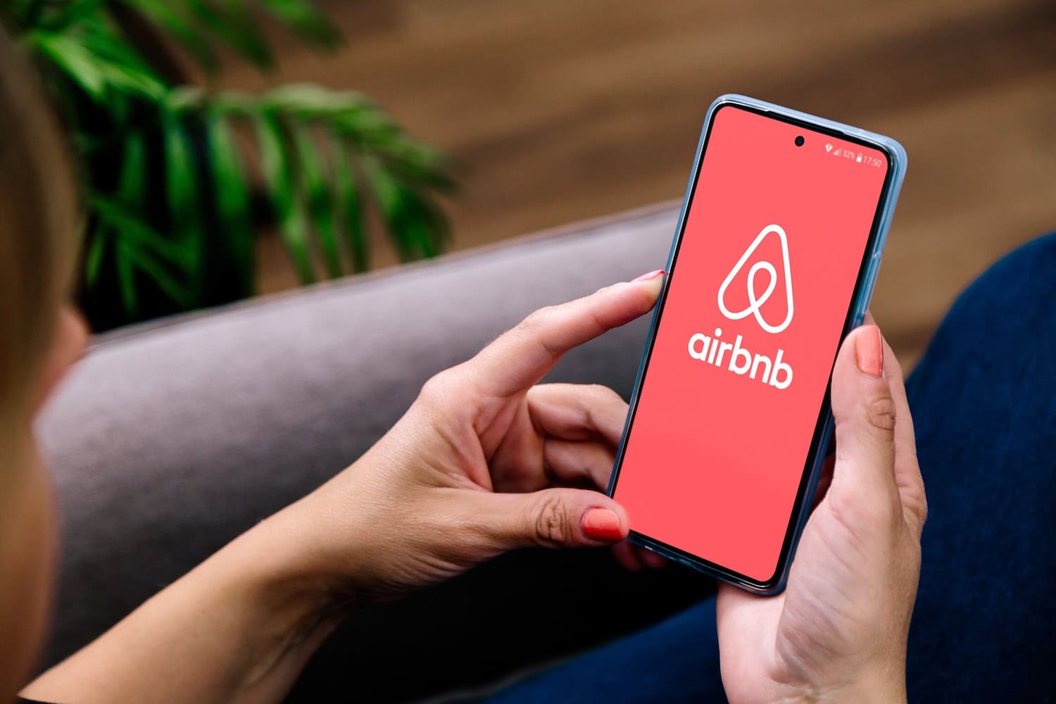 Frau hält Handy mit Airbnb App offen