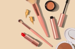 Beauty-Produkte für den Urlaub liegen auf einem hellen Untergrund