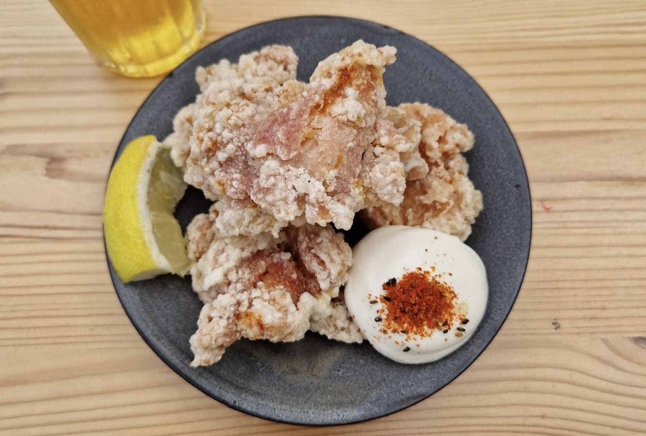 Eine Portion Karaage und ein Bier auf einem Tisch im Izakaya by Dokuwa.