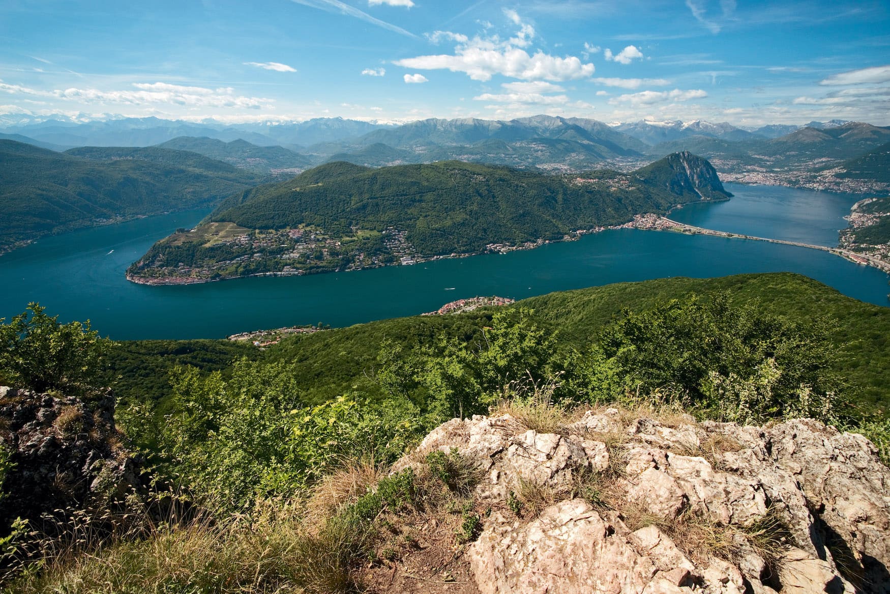 Auf dem Gipfel des Monte San Giorgio. Blick ueber den Lago di Lugano mit der Halbinsel Morcote und Monte San Salvatore