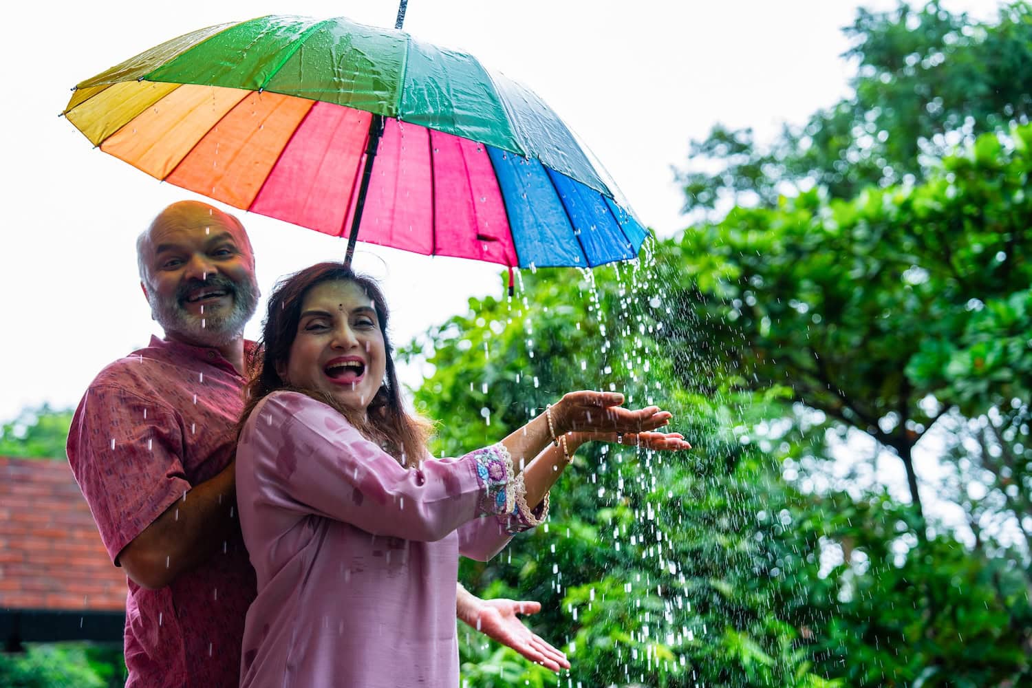 Indisches Paar mit Regenschirm im Monsun
