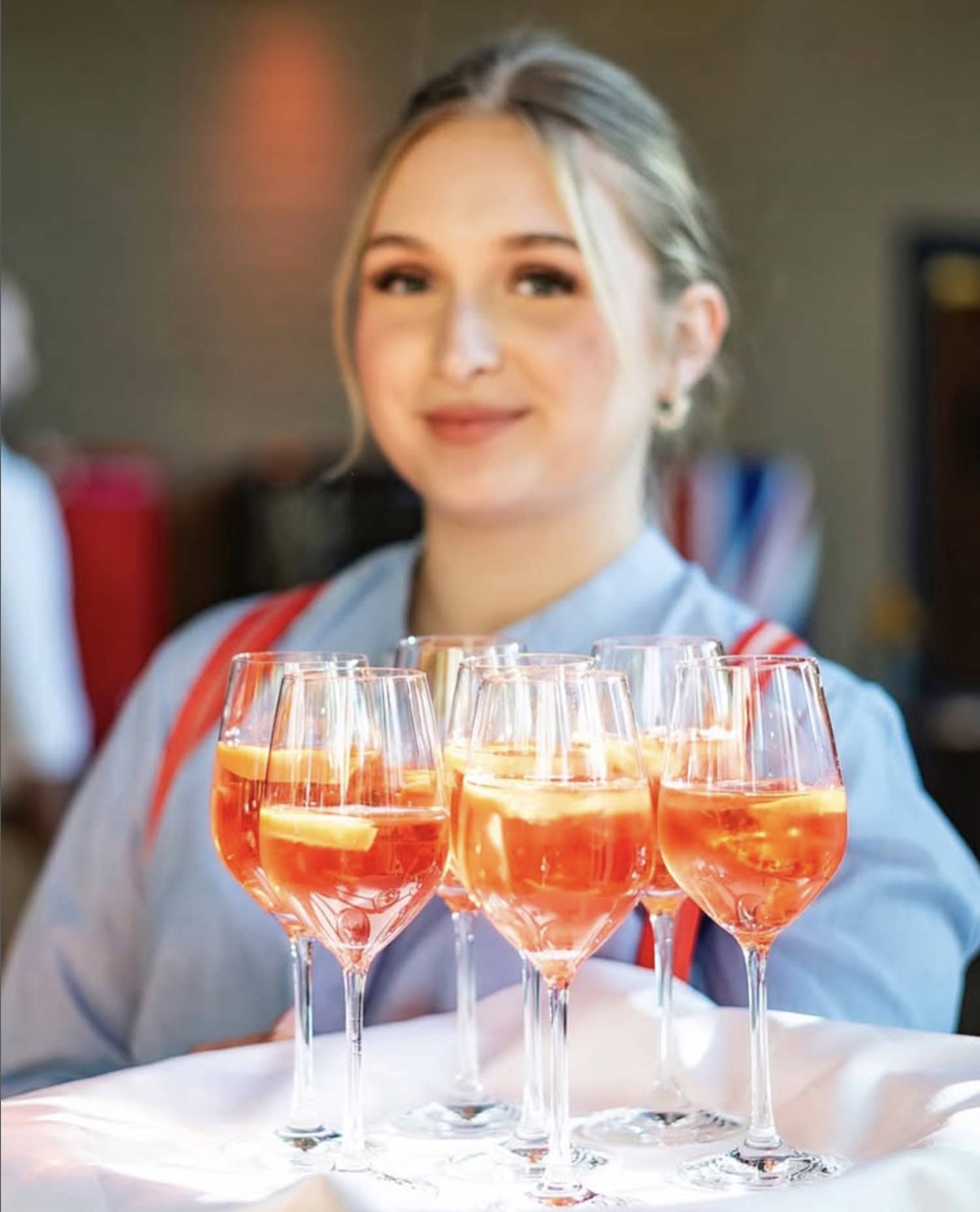 Frau hält Tablette mit Aperol Spritz bereit