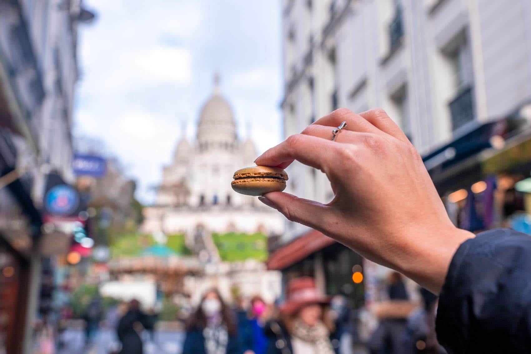 Hand, die einen französischen Macaroon-Keks präsentiert 