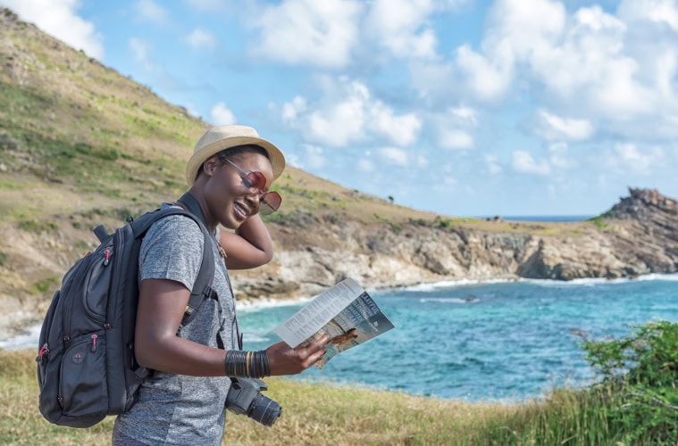 Frau hält einen Flyer in der Hand auf einem Wanderweg am Meer auf St. Maarten