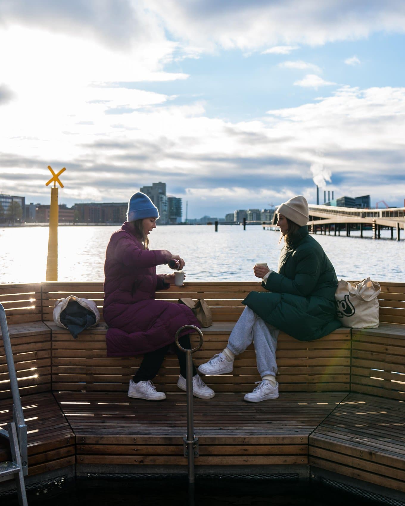 Zwei jungen Frauen sitzen in Kopenhagen an der frischen Luft und trinken einen Kaffee 
