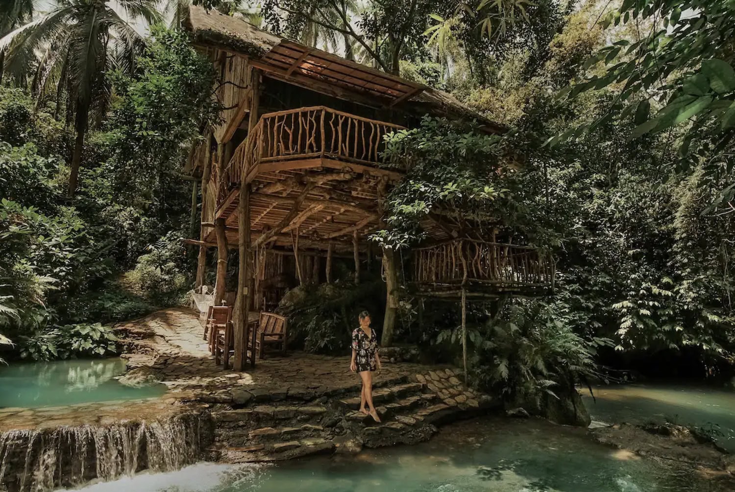 Frau vor einem Baumhaus auf den Philippinen