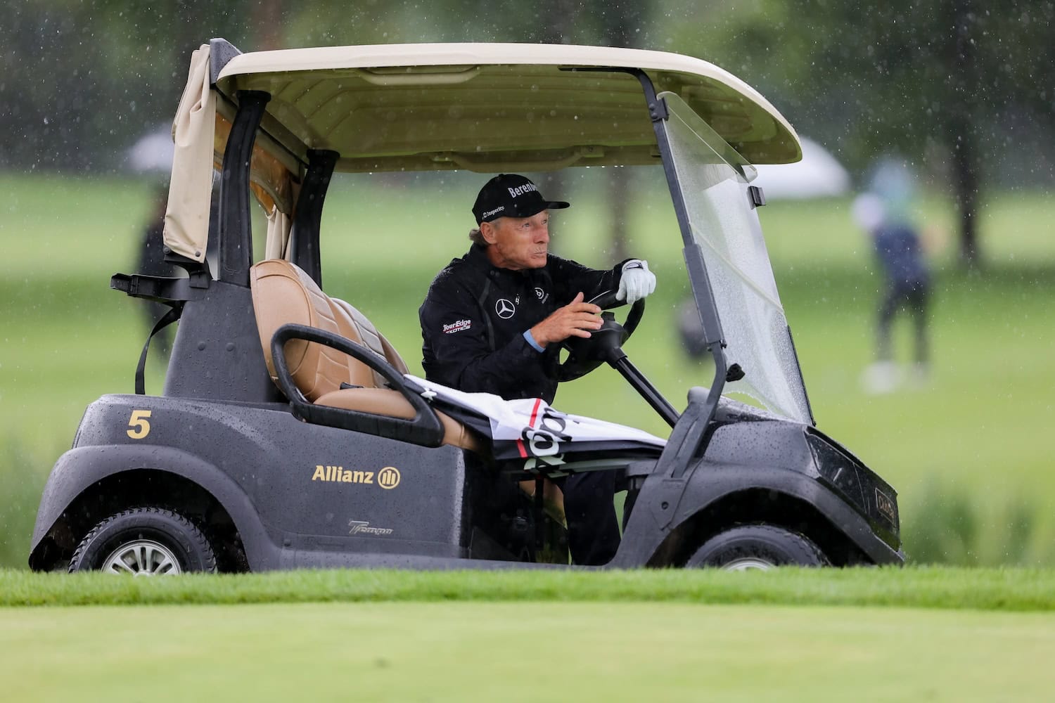 Bernhard Langer im Golfcart bei Regen.