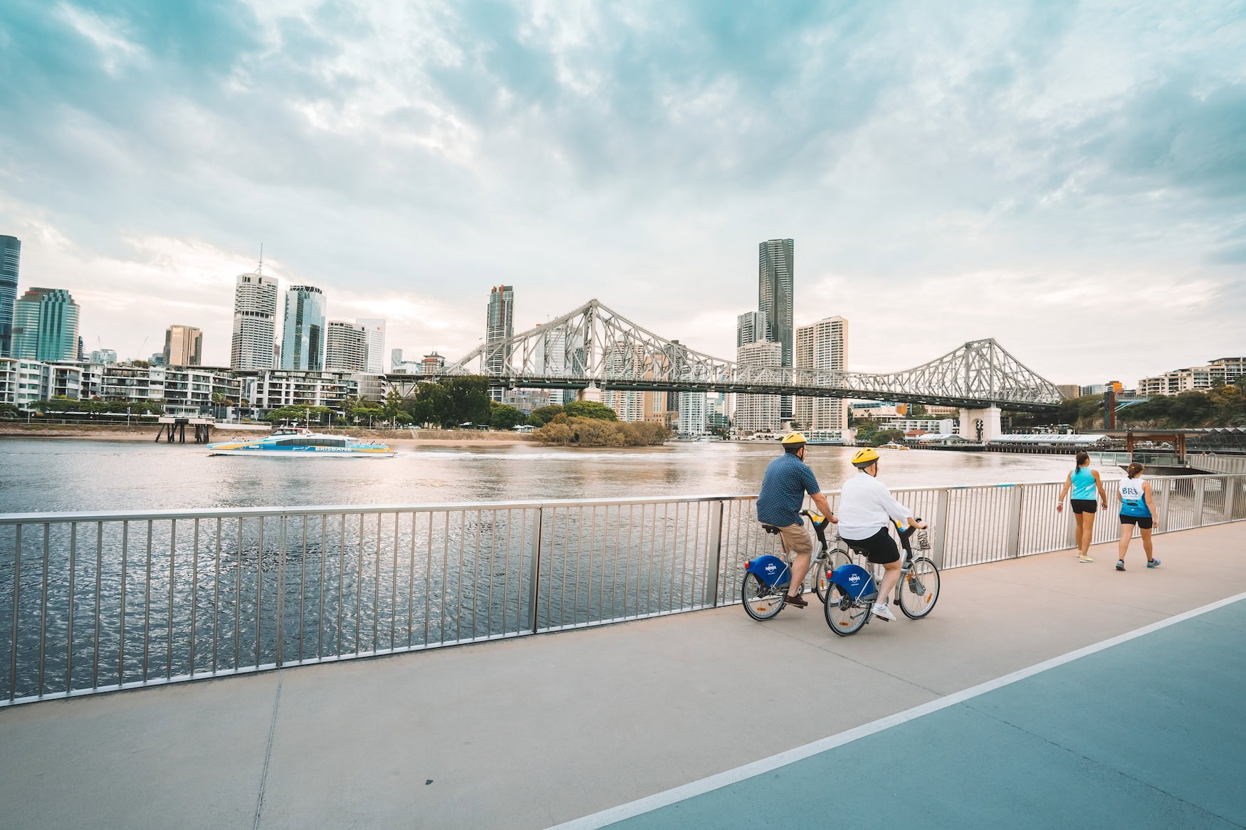 Radfahrer fahren in Brisbane am Flussufer.