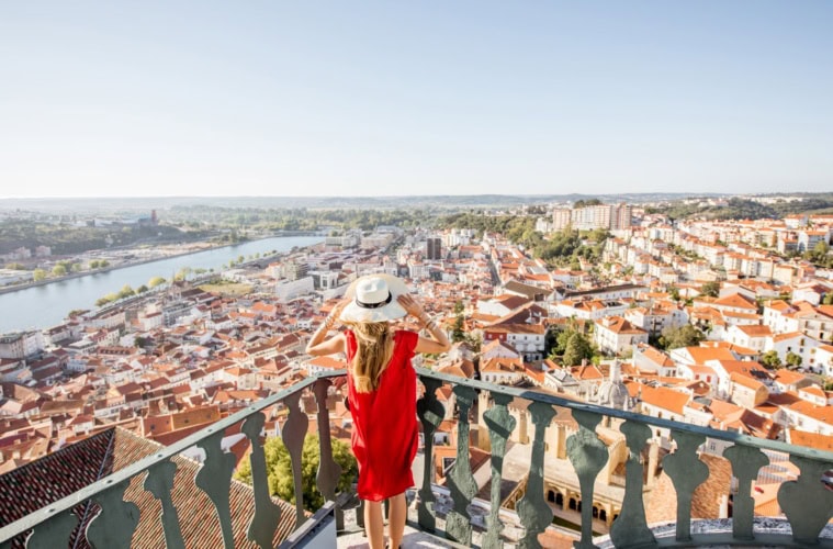 Frau mit Sonnenhut genießt Ausblick auf Coimbra, Portugal