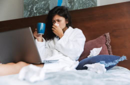 Eine Frau liegt krank im Bett. Zum Thema: Krank im Urlaub – was tun?