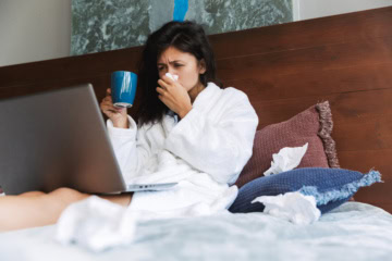 Eine Frau liegt krank im Bett. Zum Thema: Krank im Urlaub – was tun?