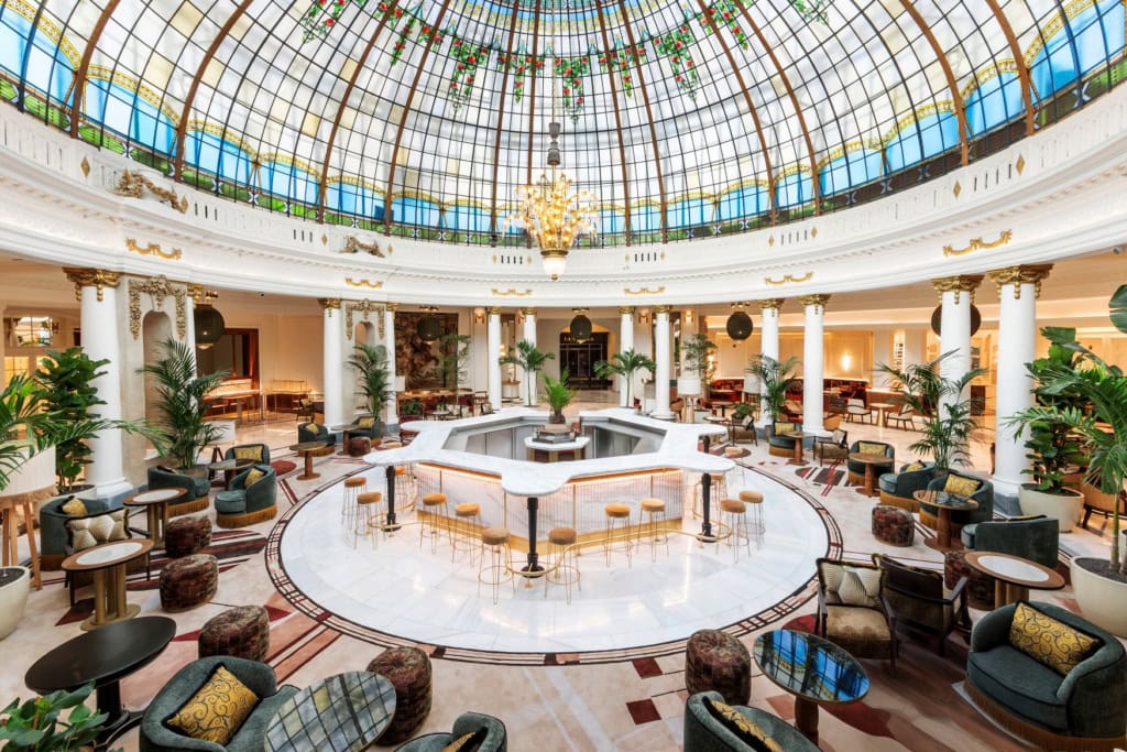 Über einem Saal mit einer zentralen, runden Marmorbar spannt eine riesige Glaskuppel im Jugendstil, in der Mitte ein großer Kronleuchter. Rund um die Bar im Zentrum sind zahlreiche Sitzgruppen mit Polstermöbeln angeordnet, frei stehende Säulen bilden eine natürliche "Grenze" des Sitzbereichs.