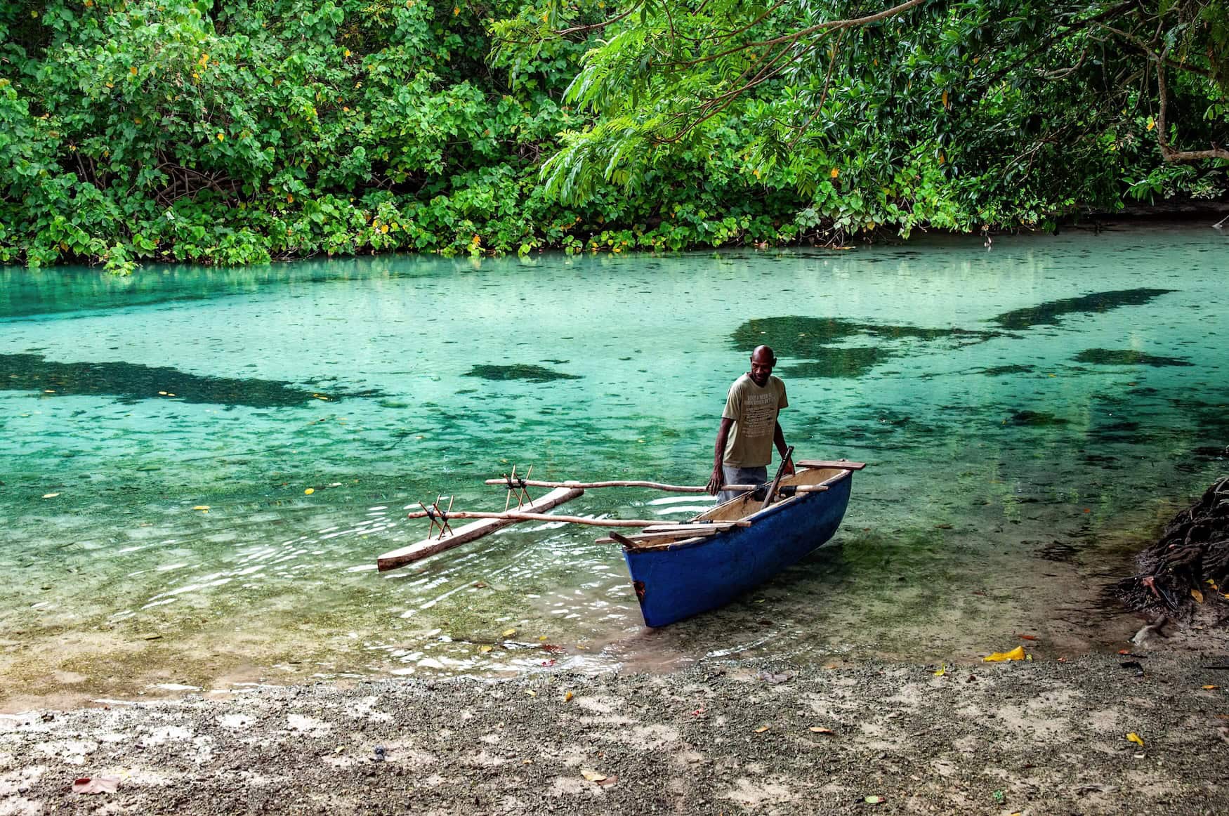 Mann mit Boot beim Anlegen in türkisfarbener Urwaldlagune