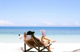 Frau im Liegestuhl am Meer beim Lesen