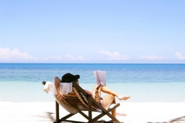 Frau im Liegestuhl am Meer beim Lesen