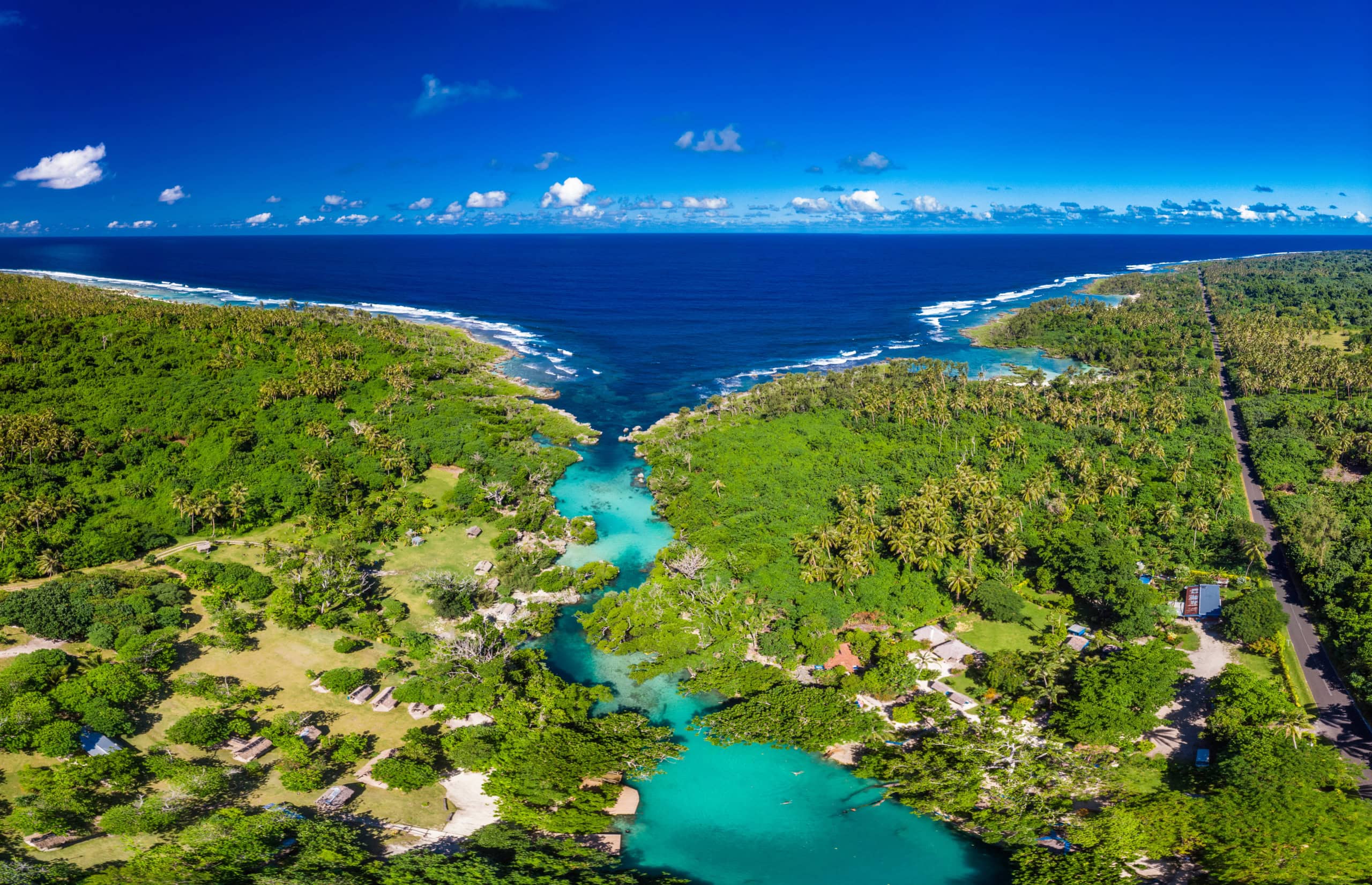Tükise Lagune von oben mit Urwald, die ins offene, dunkelblaue Meer mündet.