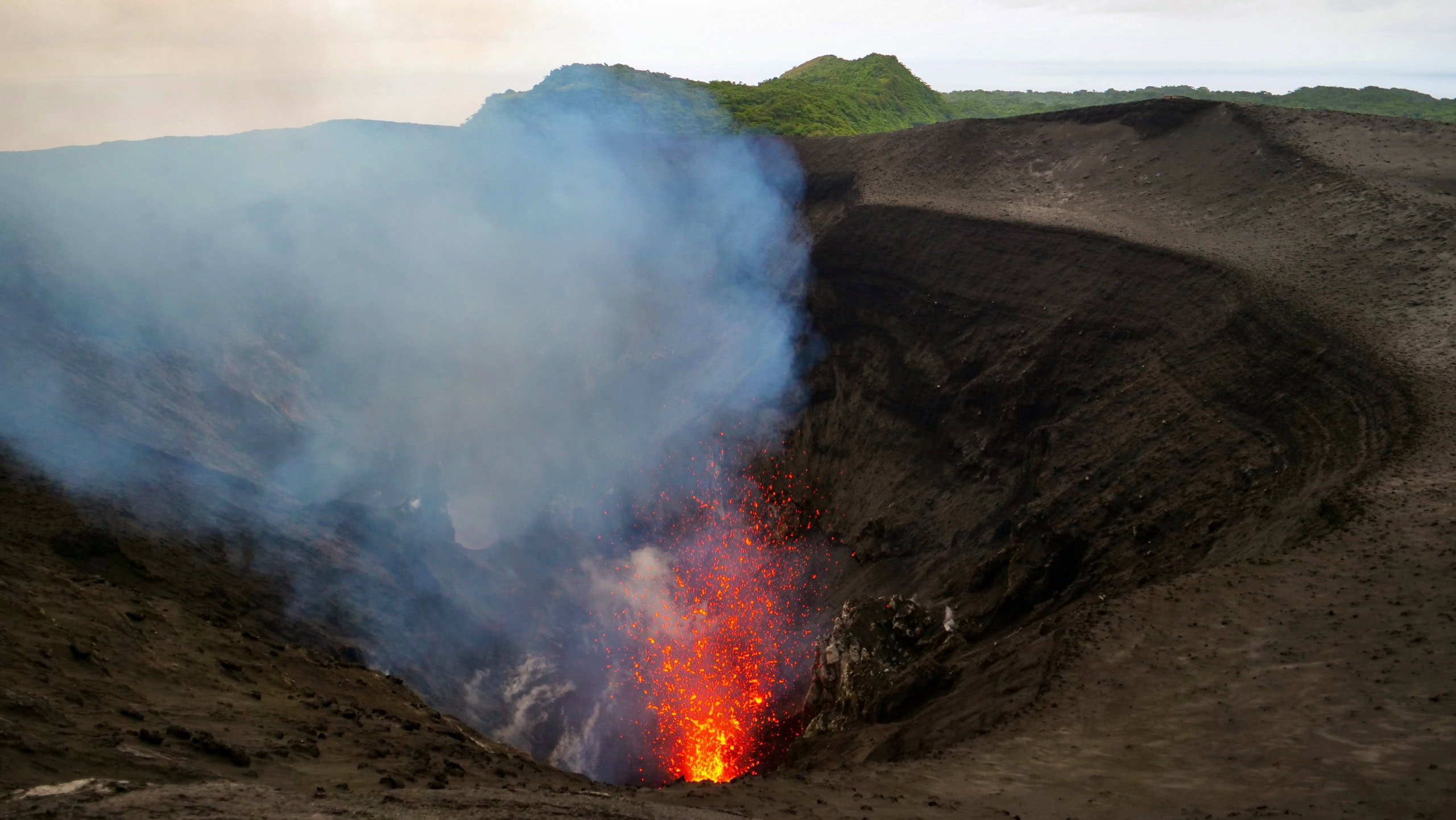 Brodelnder Vulkankrater, der Feuer spuckt mit Dampfwolke.