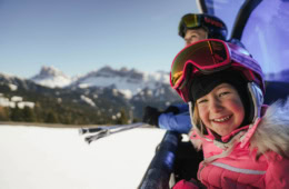 Lachendes Kind im Winterurlaub im Skigebiet Plose, Berg im Hintergrund