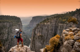Mann mit Rucksack beim Wandern im Sonnenuntergang vor gewaltiger Bergkulisse in der Türkei