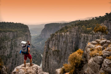 Mann mit Rucksack beim Wandern im Sonnenuntergang vor gewaltiger Bergkulisse in der Türkei