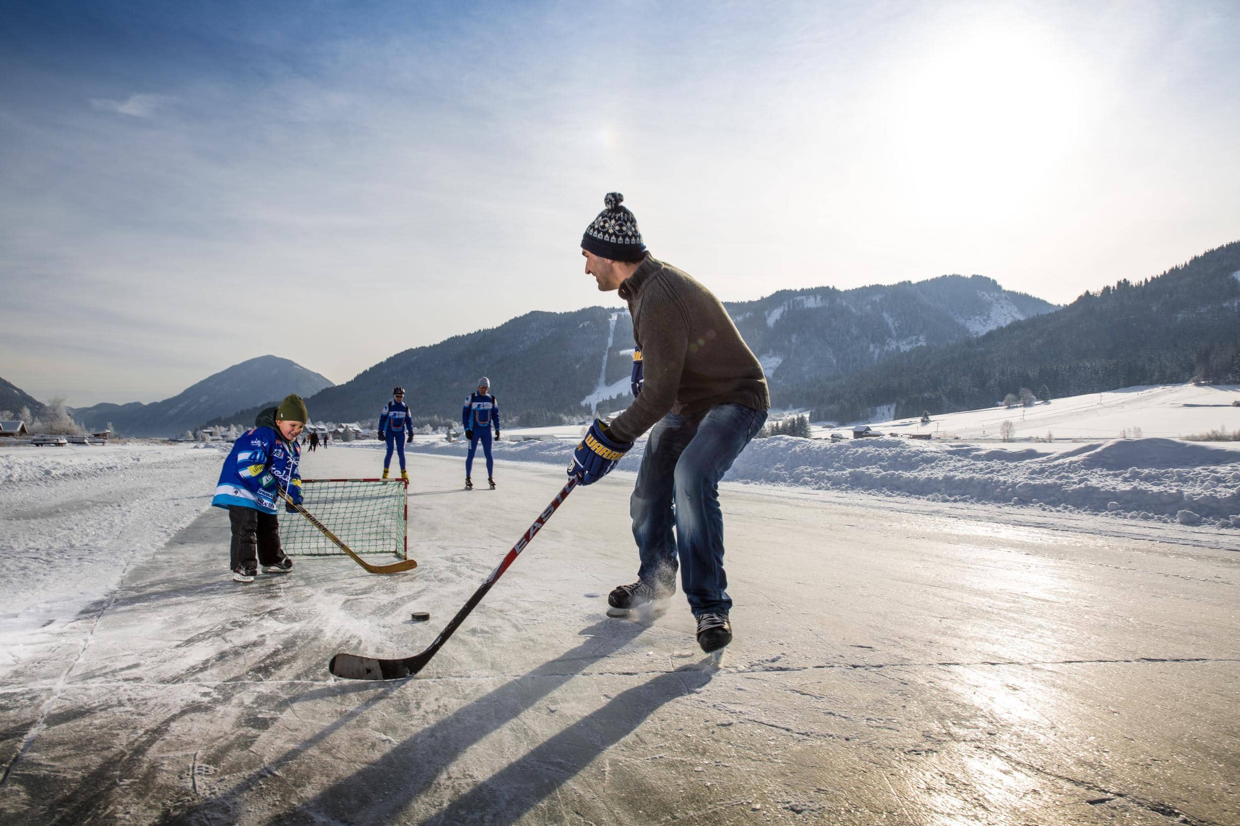 Ein Kind und ein Erwachsener spielen Eishockey am Weissensee in Kärnten.