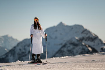 Frau im Bademantel auf Skiern