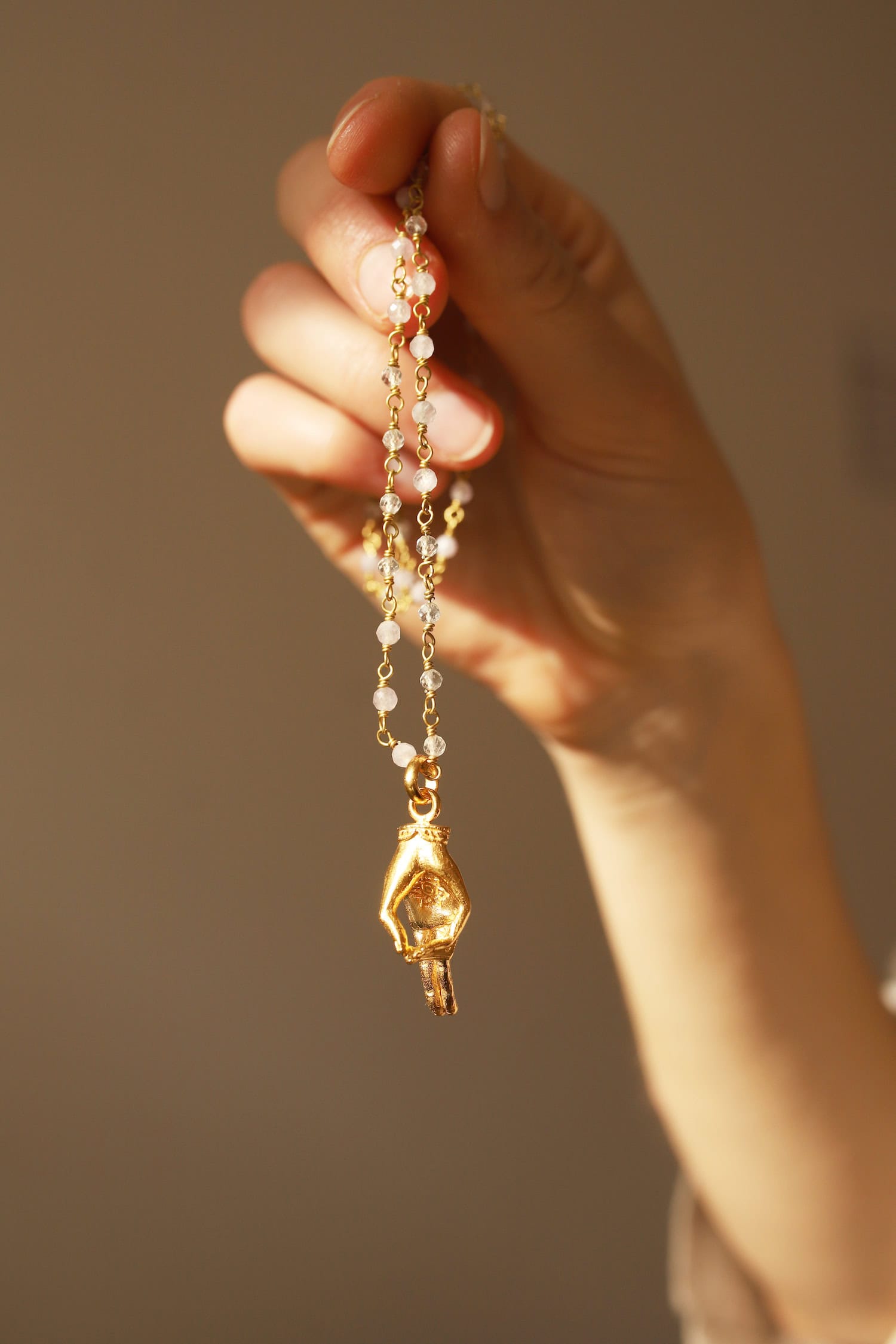 Hand hält goldenen Anhänger