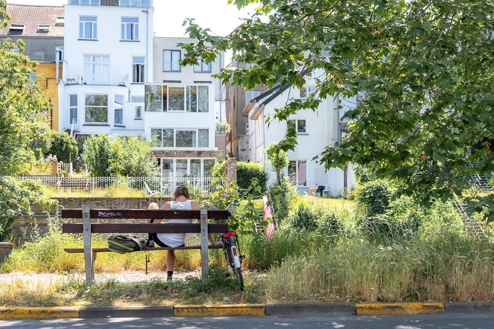 Mann sitzt auf Parkbank am Ufer der Leie in Gent