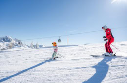 Eine Erwachsene und ein Kind fahren am Nassfeld Ski.