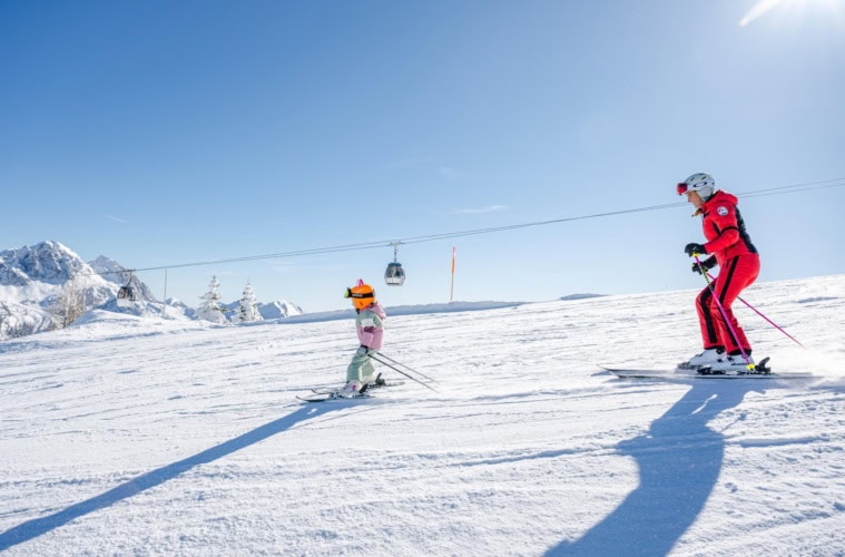 Eine Erwachsene und ein Kind fahren am Nassfeld Ski.